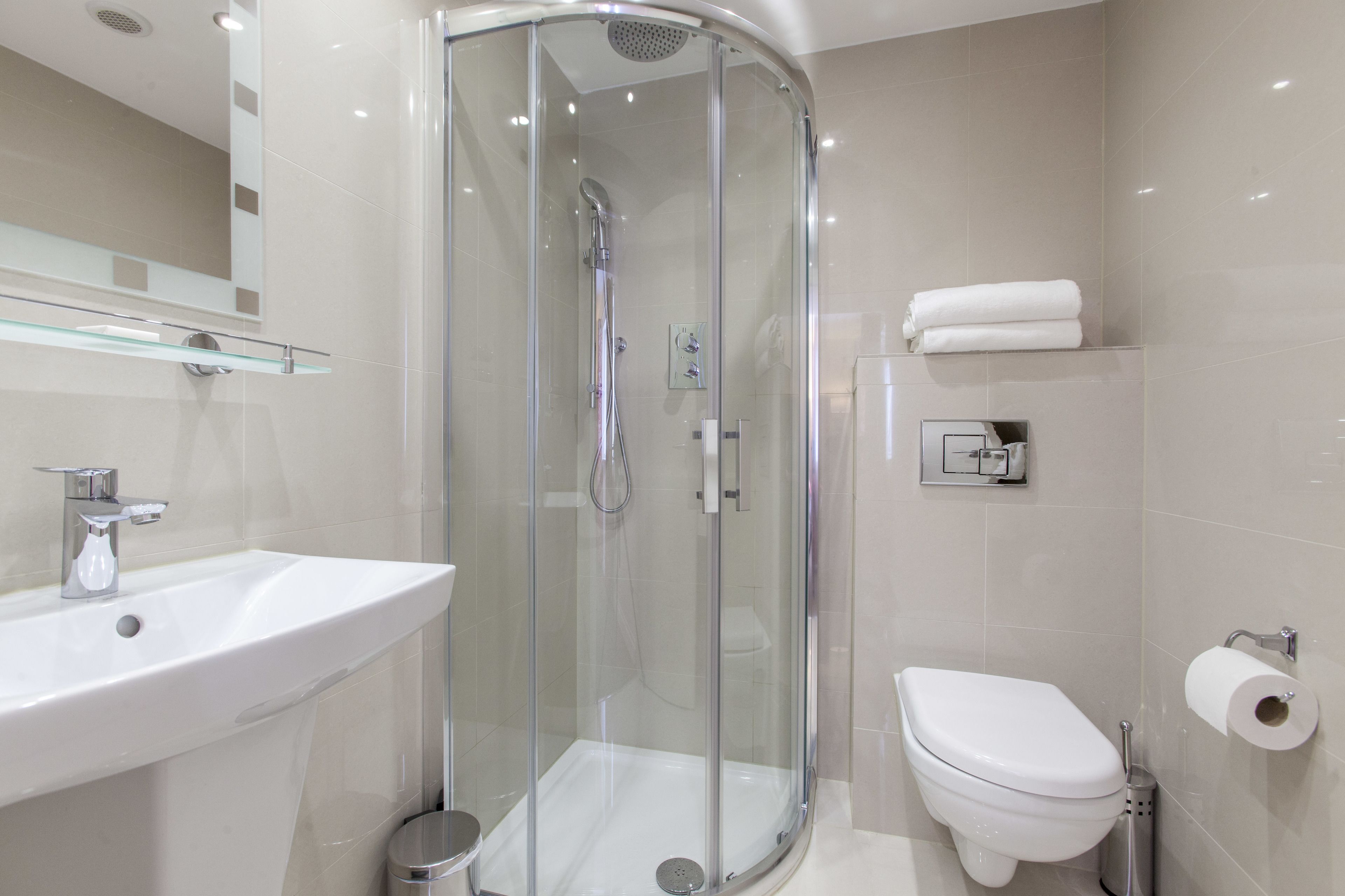 A modern bathroom with a glass-enclosed shower, a white sink, and a toilet.