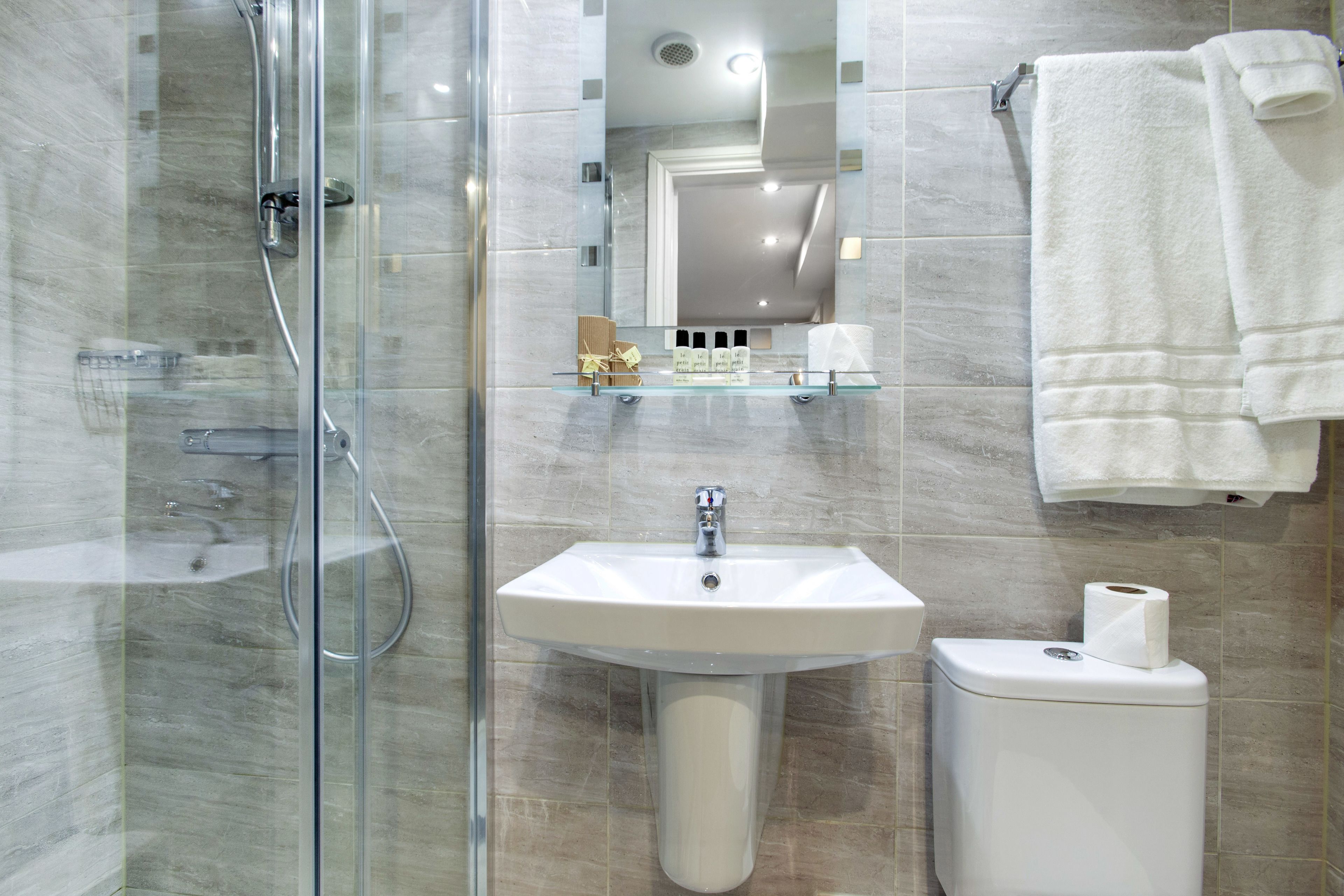 A modern bathroom with a glass shower enclosure, a pedestal sink, and a toilet.