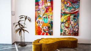 Un intérieur moderne agrémenté de deux grandes peintures abstraites au mur, d’un canapé incurvé original et d’un grand lampadaire.
