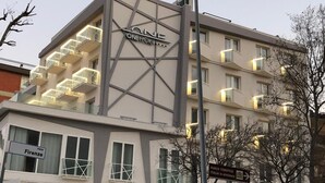 Un hôtel appelé « ONE Hotel », doté d’une architecture moderne, avec un escalier imposant et de nombreux balcons.
