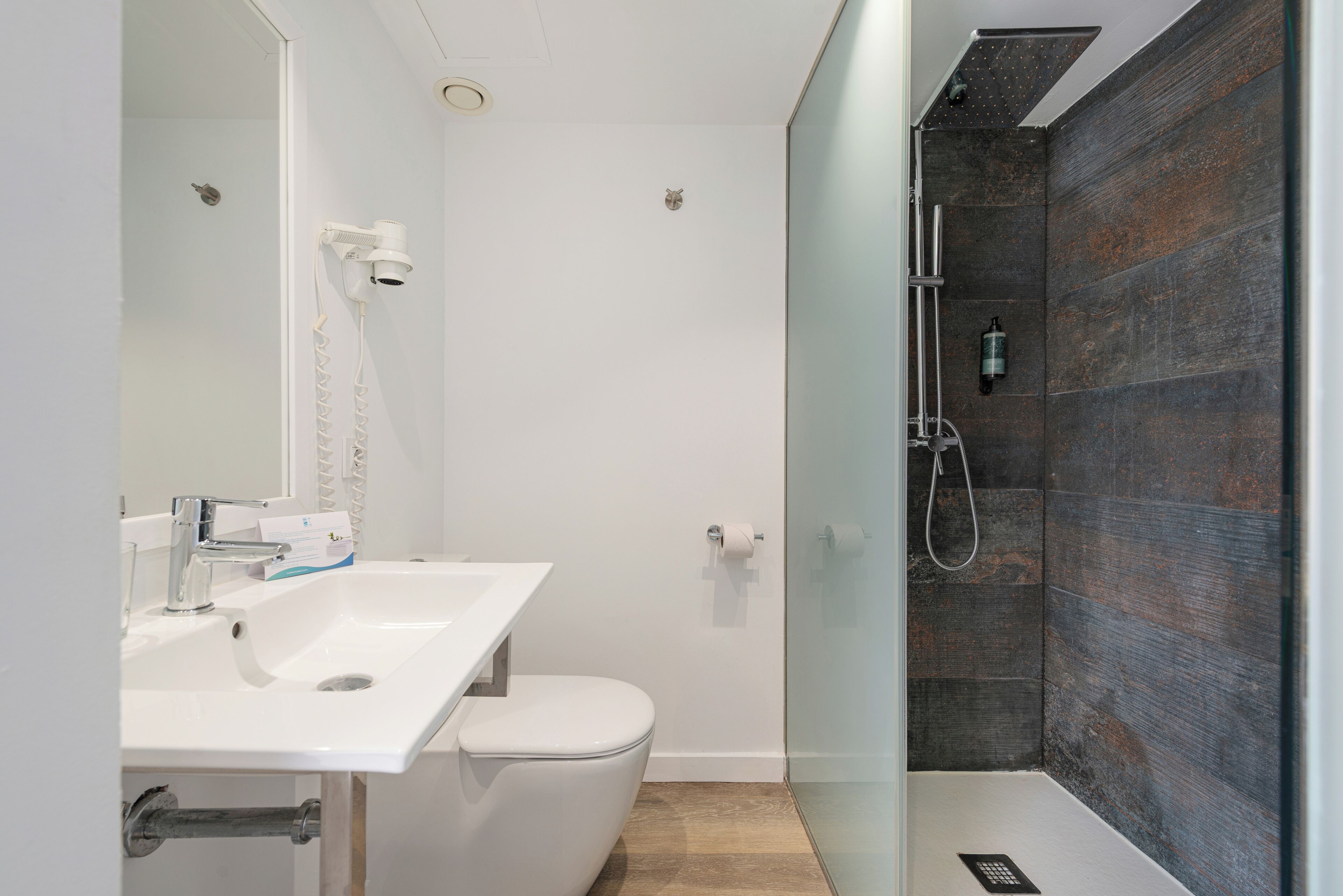 Een moderne badkamer met een wit wastafelmeubel, toilet en douchecabine.