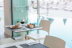 Una mesa de comedor con platos de comida, copas de vino y una planta pequeña.