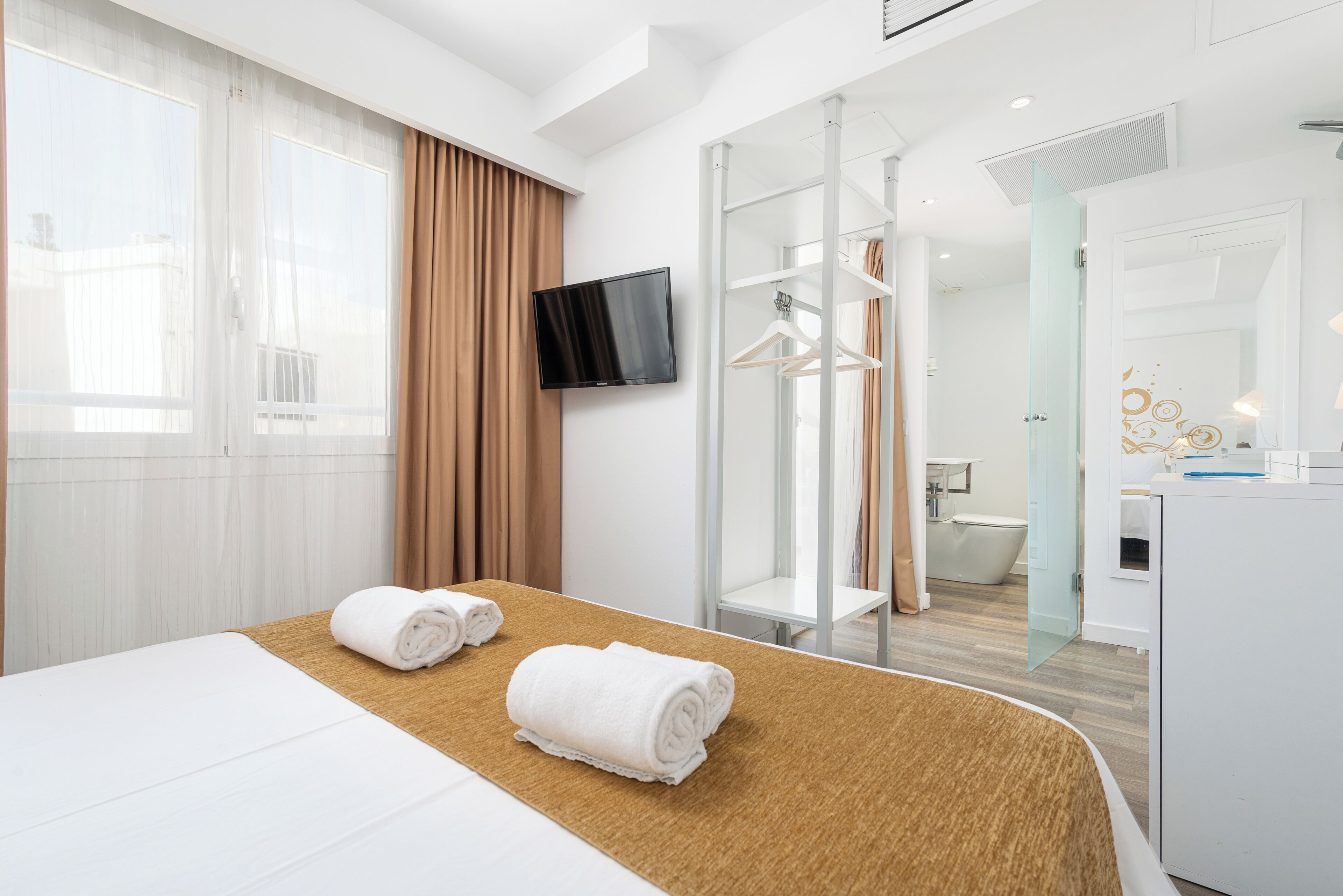 Habitación de hotel con cama, televisión, ducha y baño.
