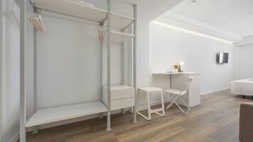 Una habitación minimalista con un armario blanco, un escritorio con silla y una cama.