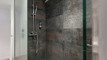 Een moderne douche met een handdouche en een kraan op de muur.