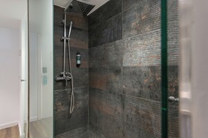 Een moderne douche met een handdouche en een kraan op de muur.