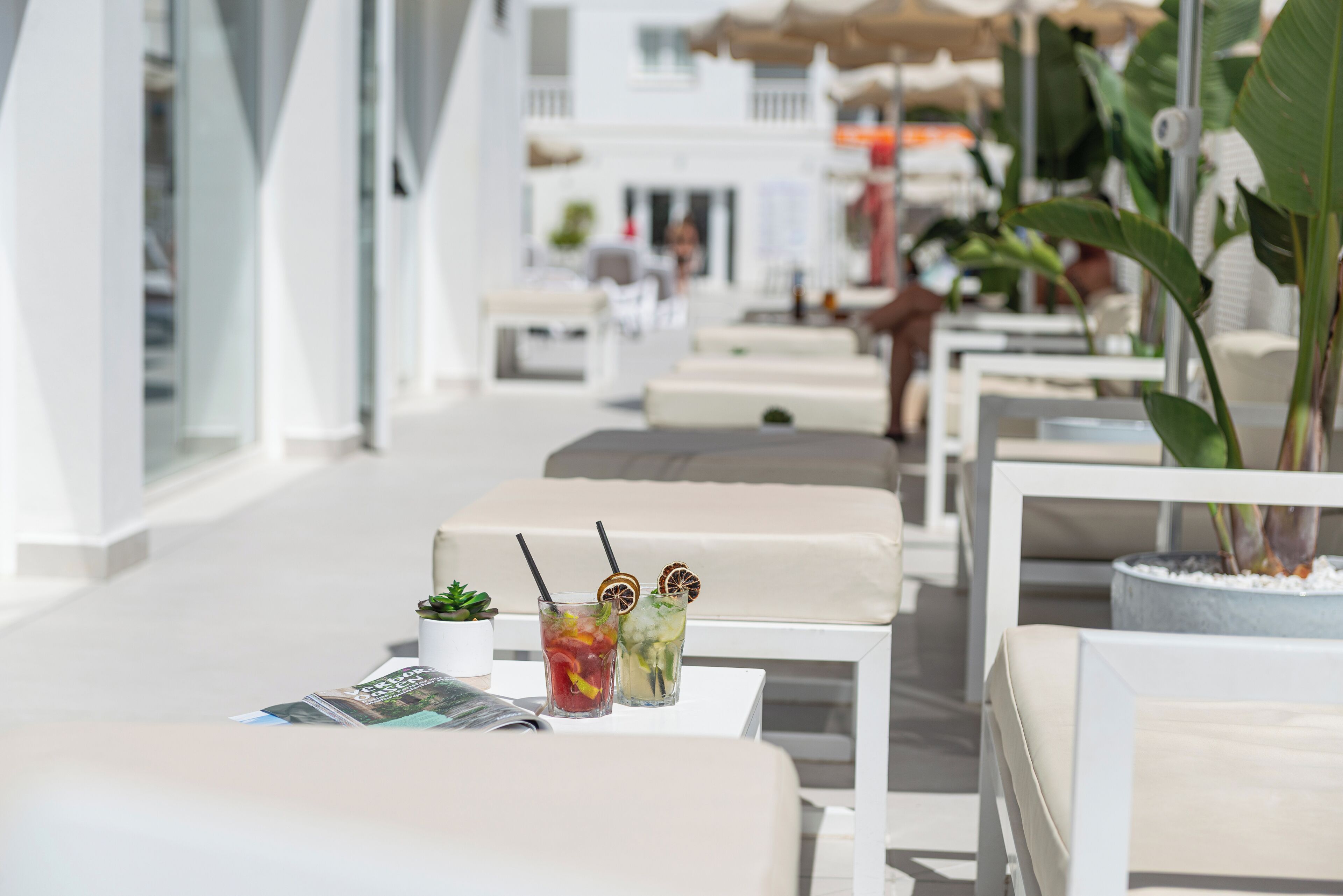 Una fila de sillones blancos con bebidas y una revista sobre una mesa.