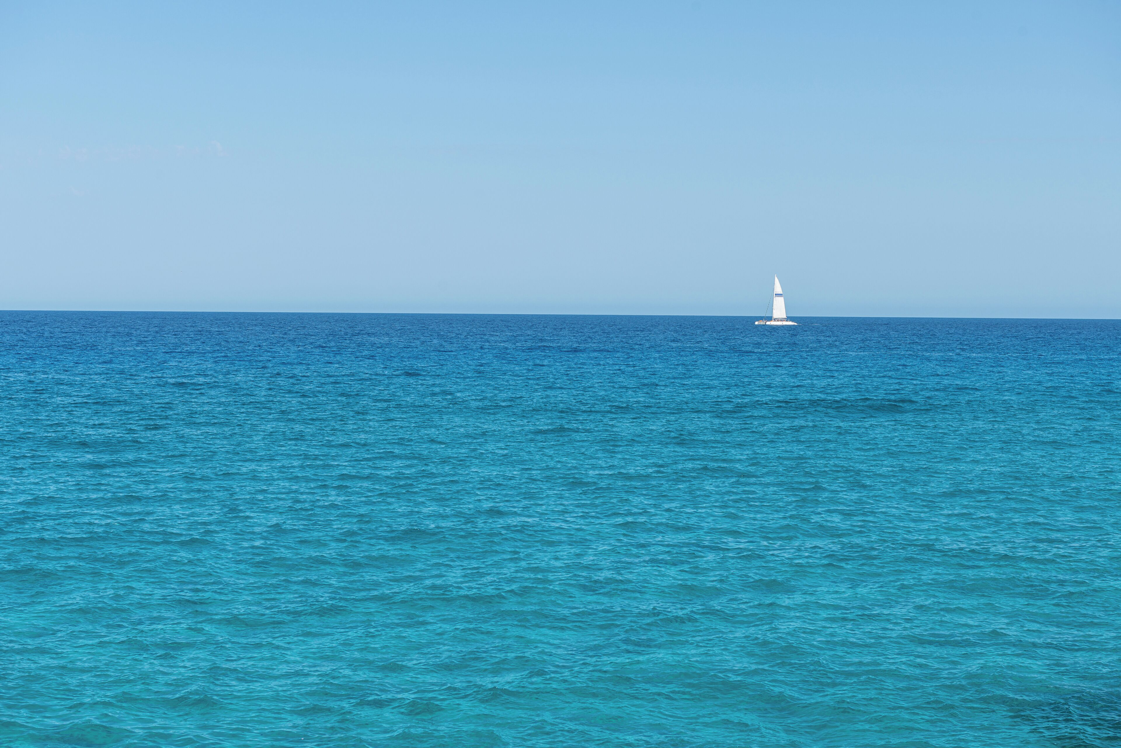 Un mar tranquilo con un faro a lo lejos.