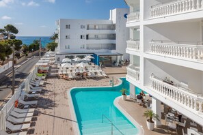 A hotel with a pool area, outdoor seating, and a view of the sea. - Welikehotel Triton Beach  (Cala Ratjada)