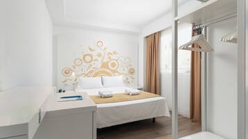 Een hotelkamer met een bed, een bureau, een kledingkast en een raam met gordijnen.