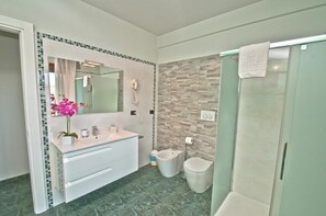 A modern bathroom with a marble floor, a white vanity with a mirror, a bidet, and a glass shower enclosure. - Hotel delle Alpi (Turin)