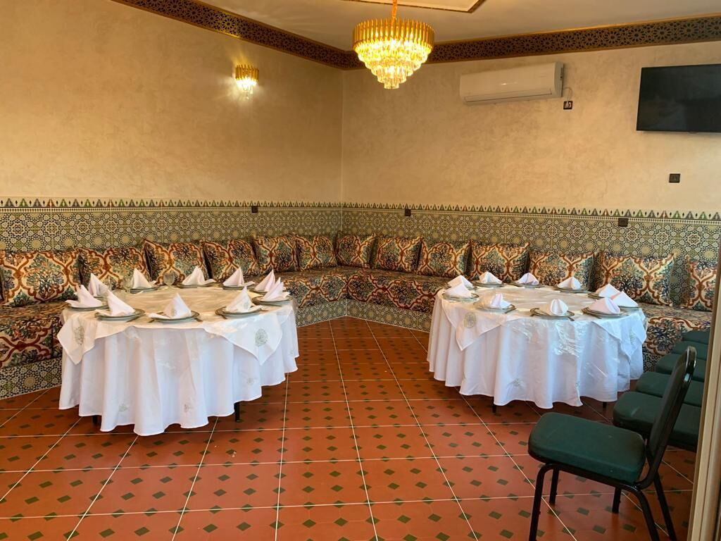 A banquet hall with two round tables set for dining, a patterned wall, and a chandelier.