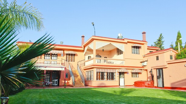 A two-story building with a red roof, multiple balconies, and a well-maintained lawn.