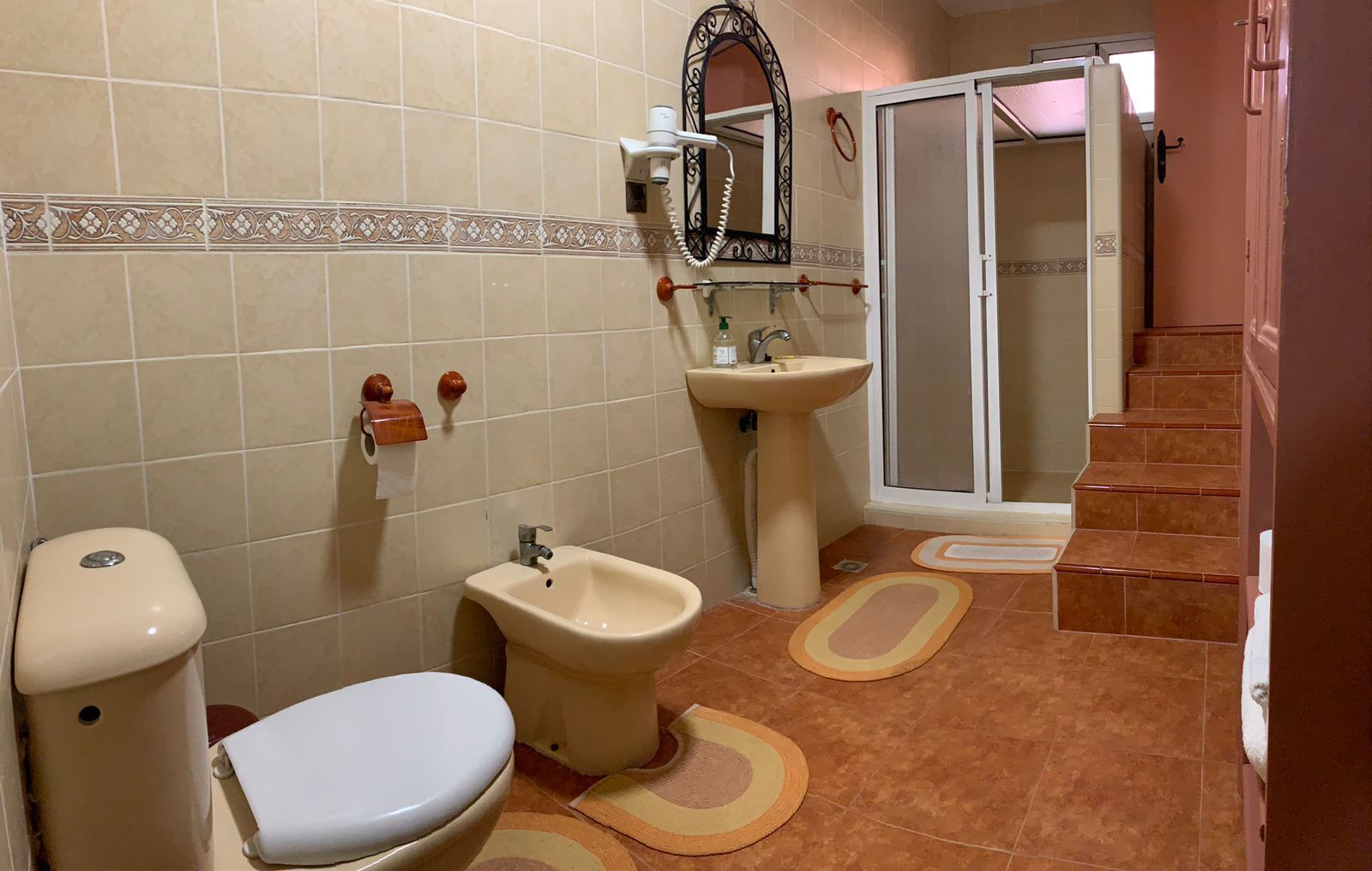 Un baño con inodoro, bidé, lavamanos y zona de ducha.