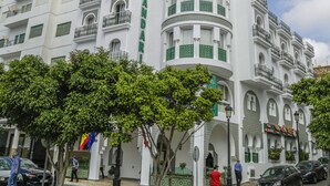 A multi-story hotel with a white facade and green accents, featuring balconies and arched windows. - Hôtel al Mandari (Tetouan)