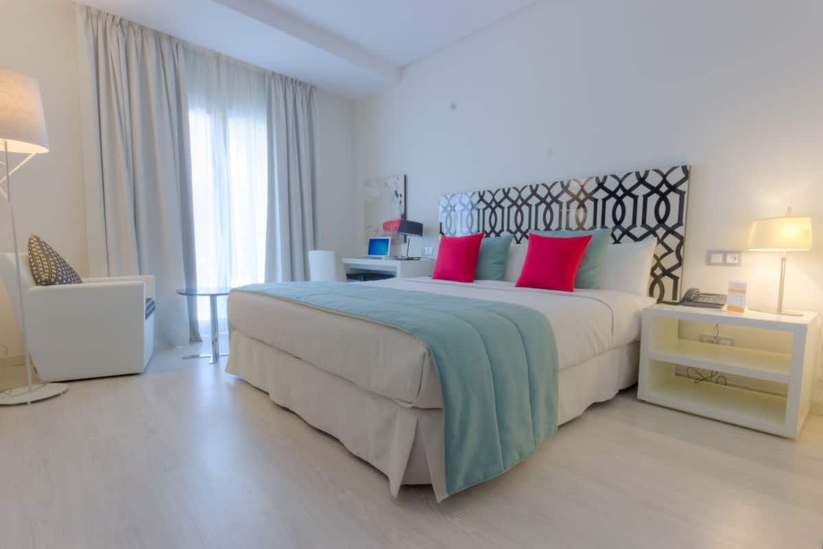 Una habitación de hotel moderna con una cama grande, un escritorio, una silla y una mesita de noche.