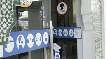 L’entrée d’un hôtel, avec des portes en verre, une affiche indiquant les mesures de sécurité liées à la COVID-19 et un panneau Visa.