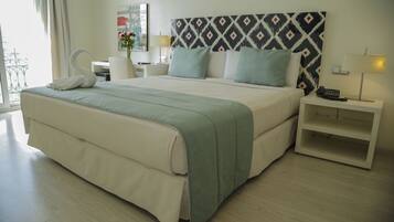 Quarto de hotel com cama grande, mesa de cabeceira, escrivaninha e uma cadeira.