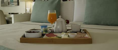 A hotel room with a bed, a tray with breakfast items, a wall with a geometric pattern, and a painting on the wall.