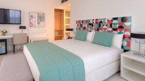 A modern hotel room with a large bed, a desk, a chair, a TV, and a colorful abstract painting on the wall. - Hôtel al Mandari (Tetouan)