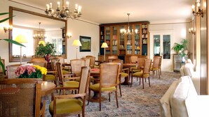 Un comedor con sillas y mesas de madera, un candelabro y una estantería.