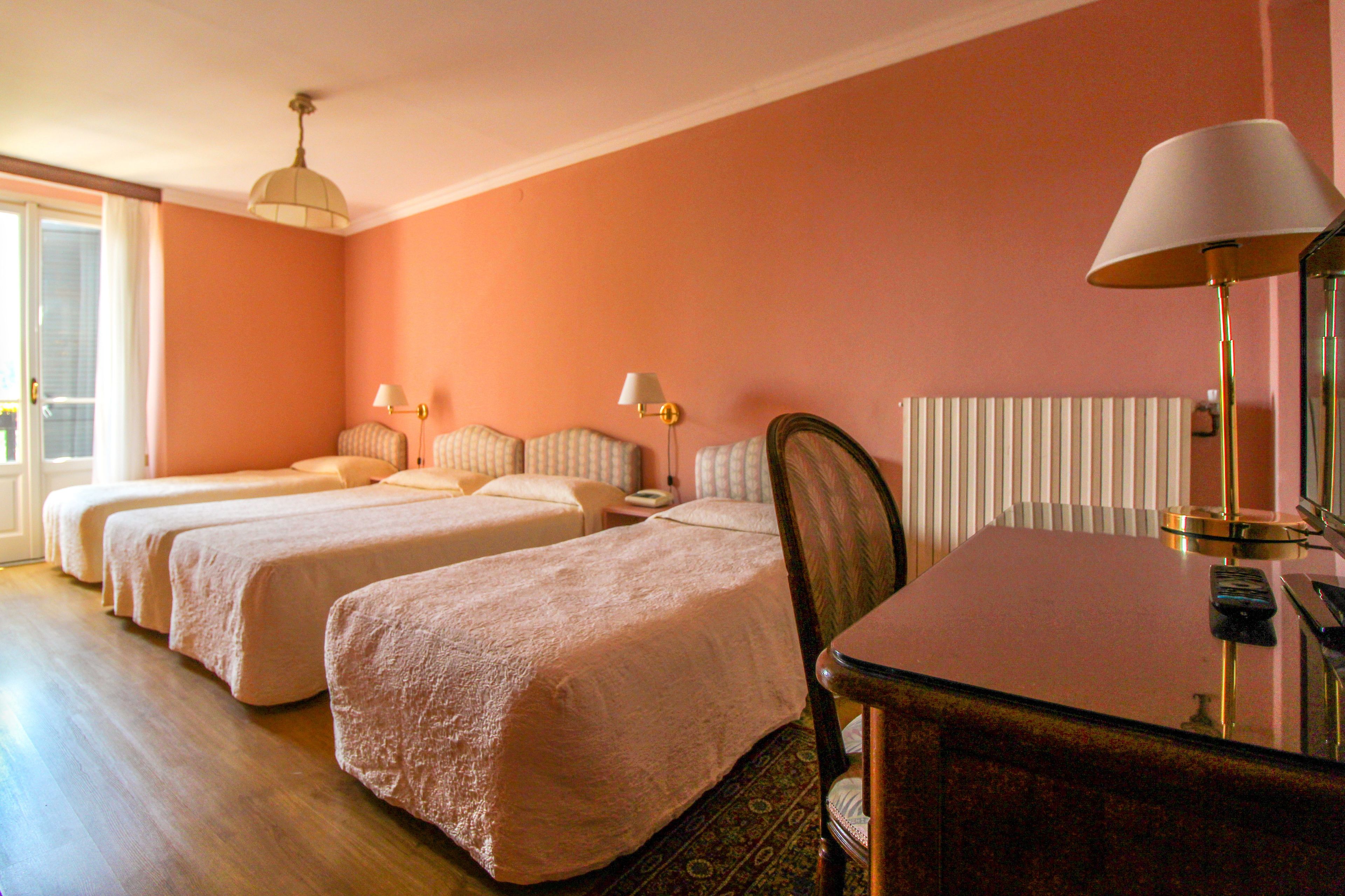 Een hotelkamer met twee bedden, een bureau en een stoel.