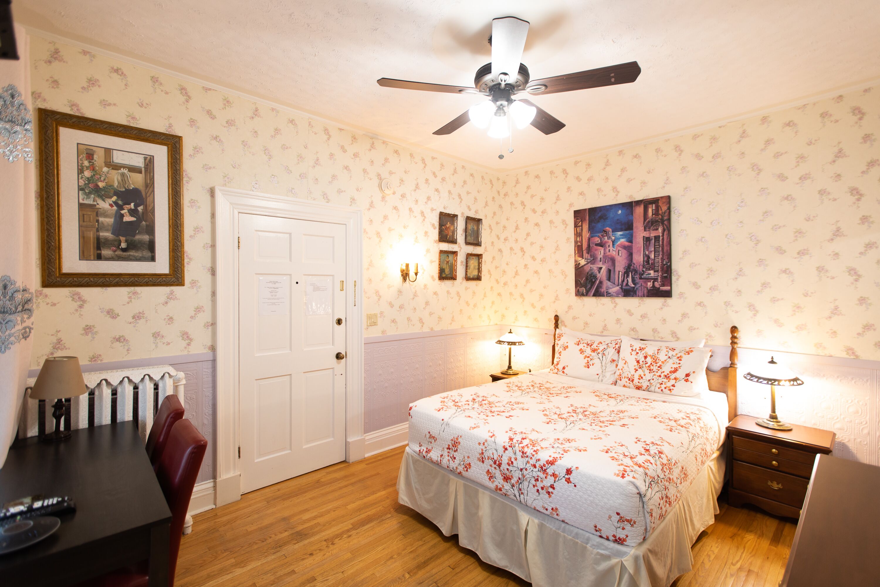 A bedroom with a bed, bedside tables, a desk, and a chair.