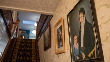 Una escalera con alfombra estampada y una pared con retratos enmarcados.