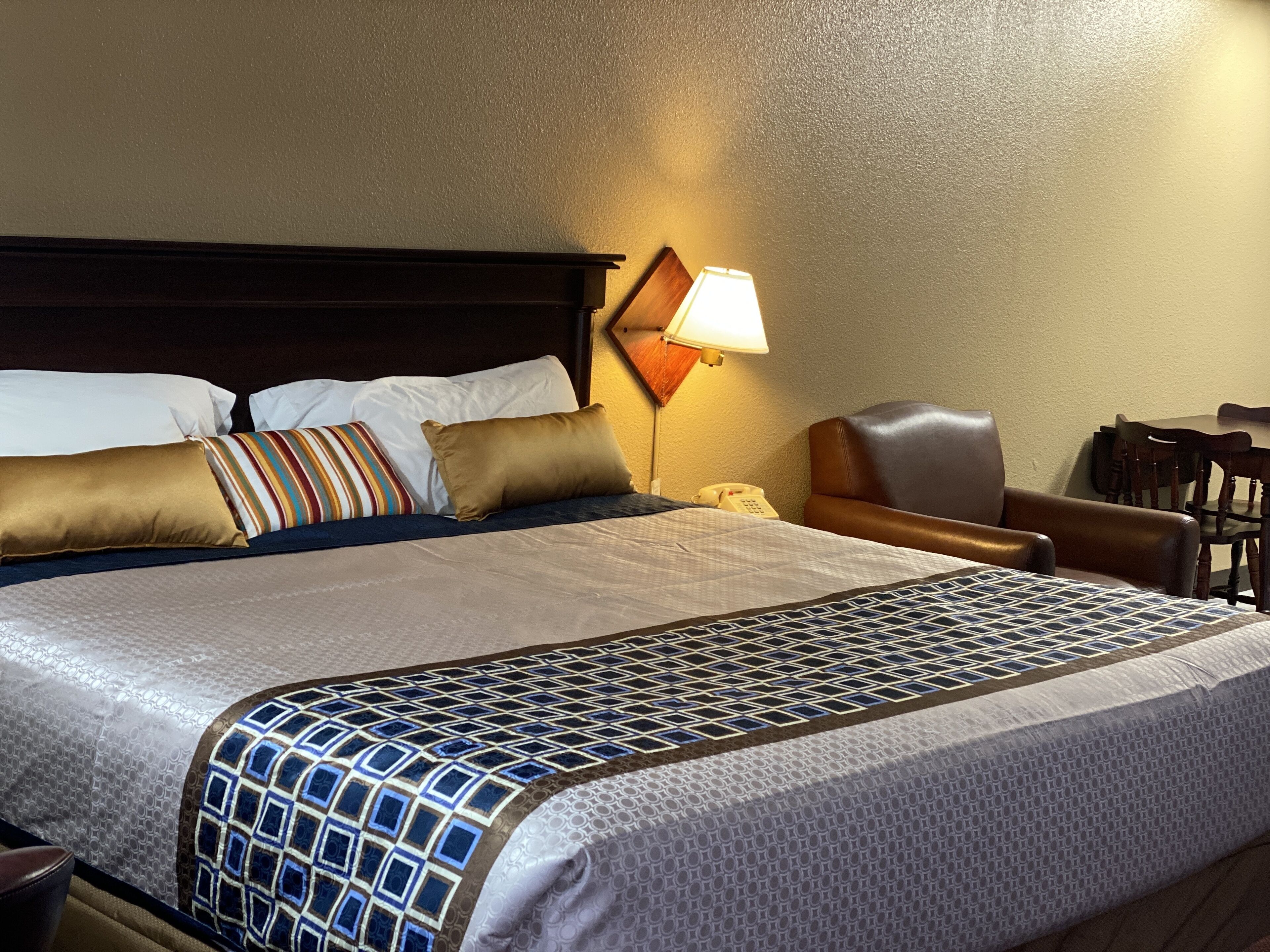 Una habitación de hotel con una cama grande, un escritorio, una silla y una lámpara.