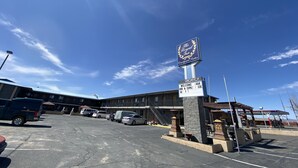 A hotel with a sign indicating no vacancy, a parking lot with several cars, and a clear blue sky.
