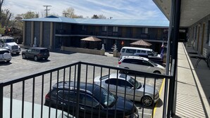 A motel with a parking lot, multiple vehicles, and a building with a blue roof.