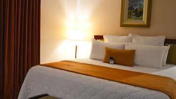 A hotel room with a bed, a nightstand, a lamp, and a painting on the wall.
