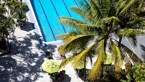 A rectangular swimming pool with a tiled deck, surrounded by palm trees and greenery. - Hotel Honduras Maya (Tegucigalpa)