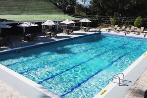 Une piscine à l’eau d’un bleu limpide, avec des chaises longues et des parasols.