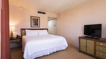 Habitació d'hotel amb un llit, una televisió sobre un moble de fusta, una tauleta de nit amb una làmpada i un quadre penjat a la paret.
