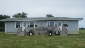 A single-story house with a front porch, a small set of steps, and two outdoor trash cans.