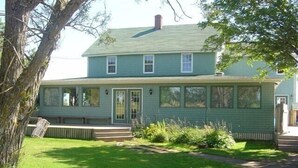 A two-story house with a green exterior, a front porch, and a well-maintained lawn.