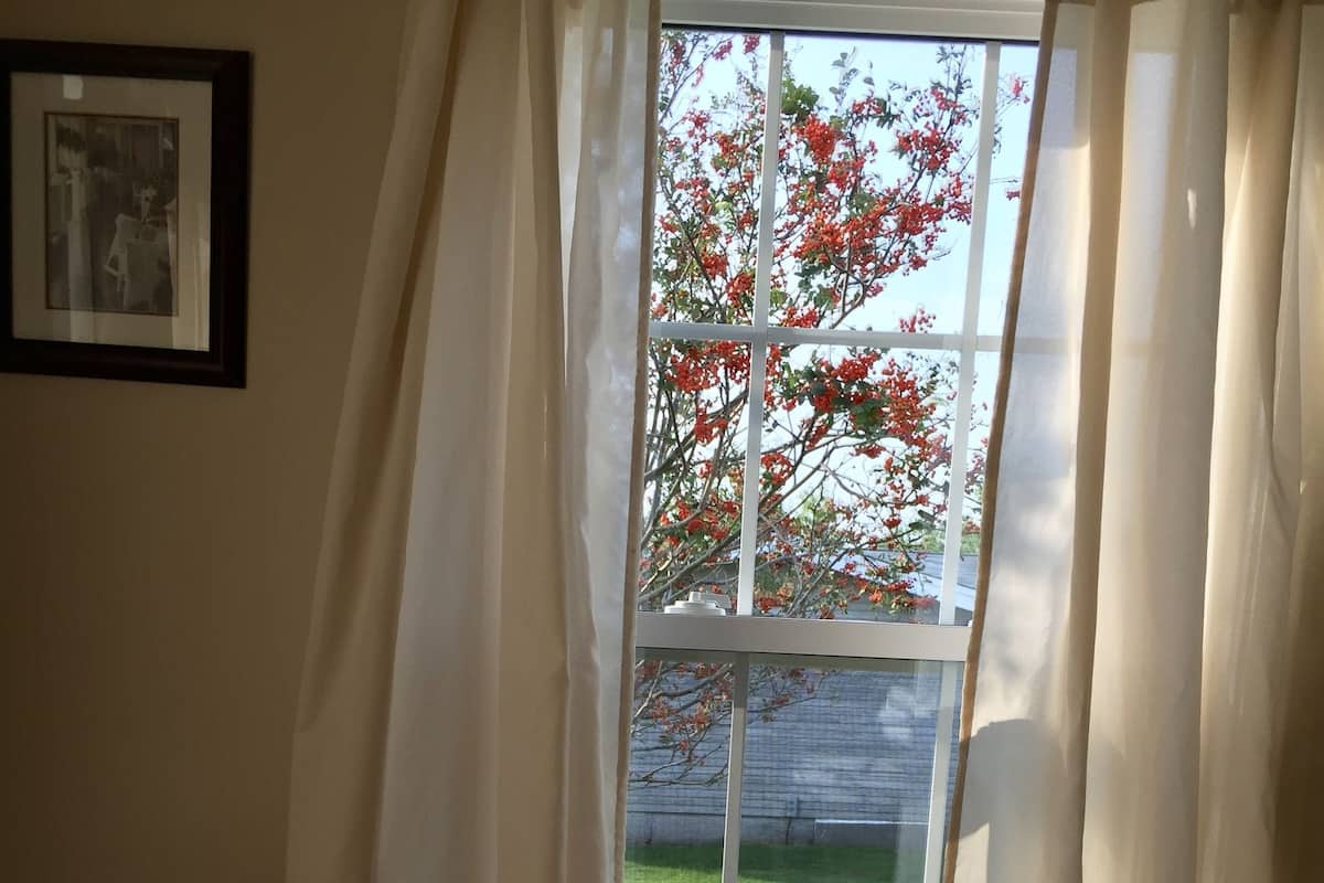 A room with a large window, a wooden chair, and a radiator.