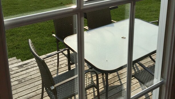 A view from a window overlooking a grassy area with a pool and outdoor furniture.