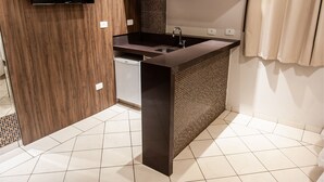 A modern kitchen with a built-in microwave, a sink, and a flat-screen TV displaying the Netflix logo. - London Hotel (Londrina)