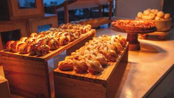 A buffet with various baked goods, including pastries and bread, arranged on wooden serving boards.
