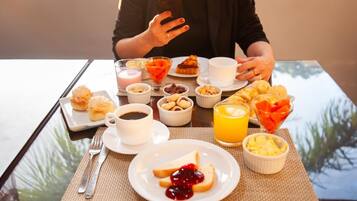 Et morgenbord med forskellig mad og en person, der bruger en smartphone.