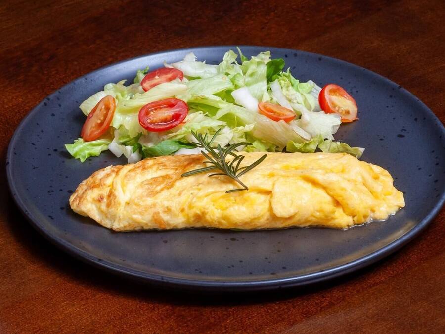 Un plato con una tortilla y una ensalada sobre un plato azul oscuro.