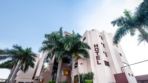 A modern hotel building with a prominent 'HOTEL' sign, surrounded by palm trees and a paved driveway. - London Hotel (Londrina)