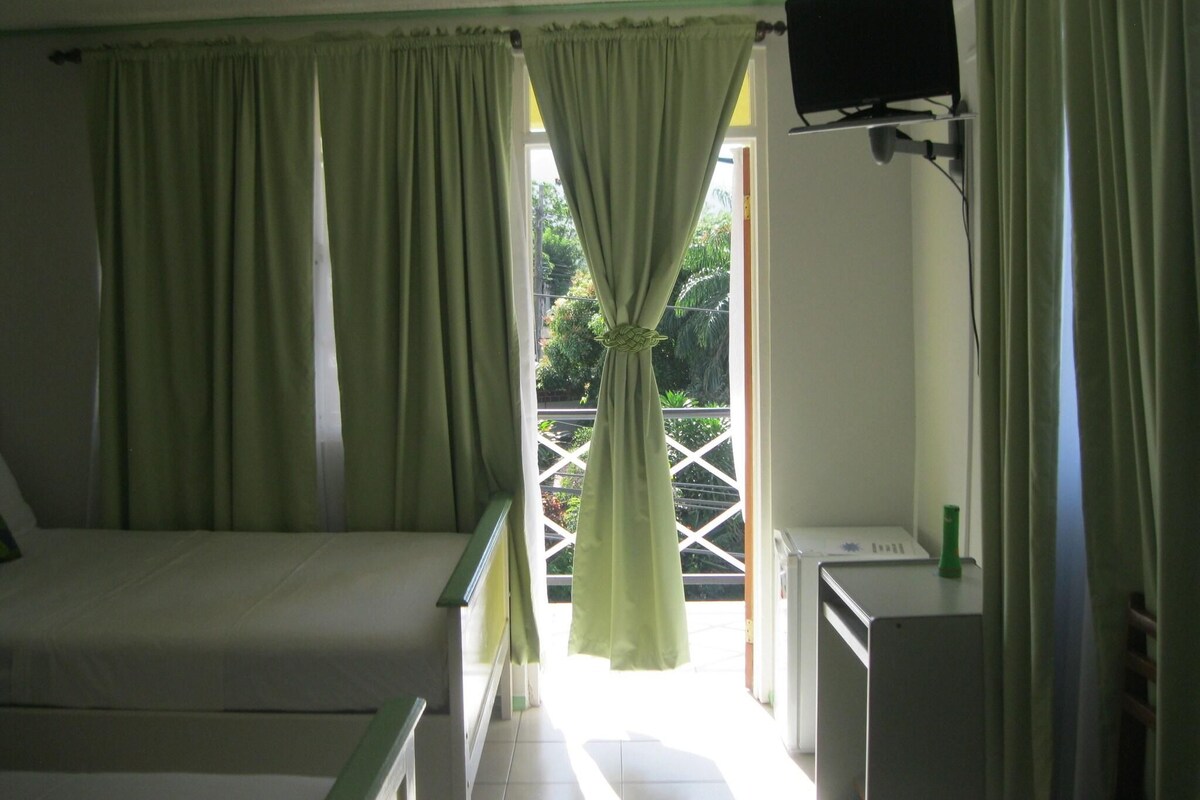 A room with a bed, a television mounted on the wall, and a window with curtains.