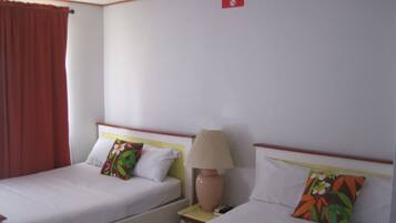 A hotel room with two beds, a nightstand, a lamp, and a 'No Smoking' sign on the wall.