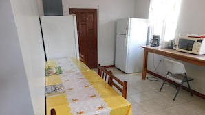 A compact kitchen with a dining area. It includes a refrigerator, a microwave, and a coffee maker. - Mr. Clean Bed and Breakfast (Roseau)
