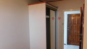 A hallway with a bench, a door with a no-smoking sign, and a wooden door with a decorative panel. - Mr. Clean Bed and Breakfast (Roseau)