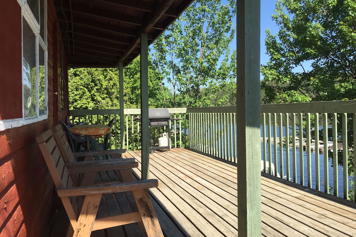 A wooden deck with a table and benches, overlooking a body of water.