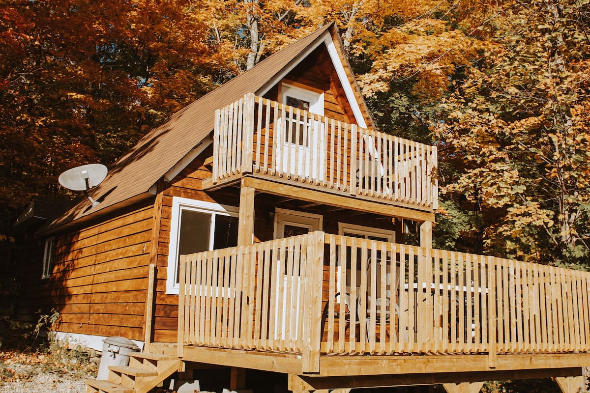A wooden cabin with a balcony and a satellite dish.